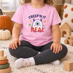 Toddler wearing the updated pink Creep'n It Real T-shirt in a cozy fall playroom